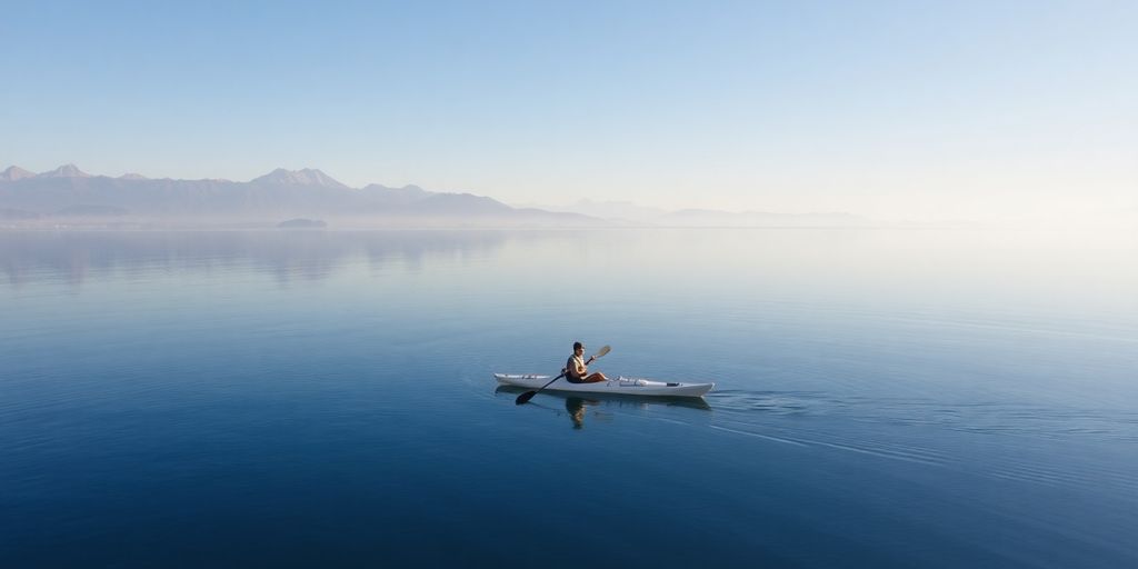 Kayaker on calm water, distant mountains